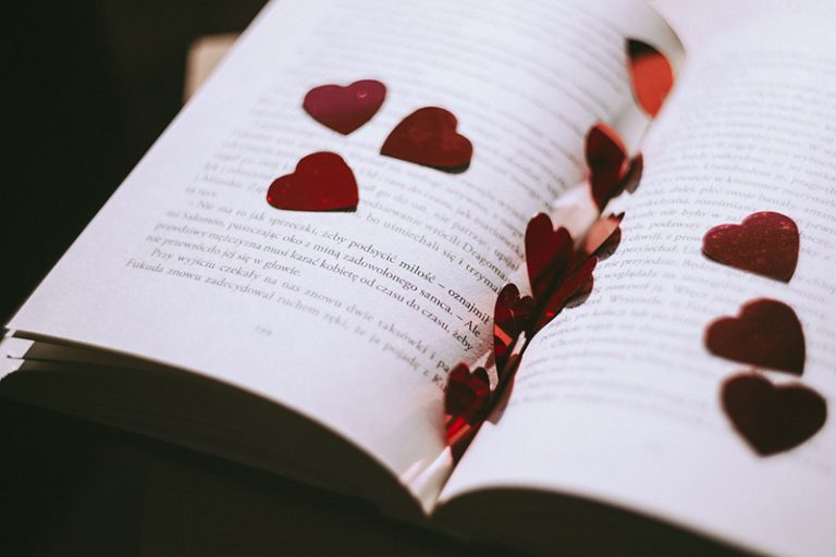 rotes herzförmiges Konfetti auf dem geöffneten Buch
