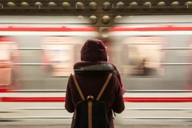 Frau mit Rucksack wartet auf den Zug
