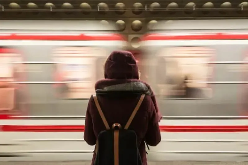 Frau mit Rucksack wartet auf den Zug