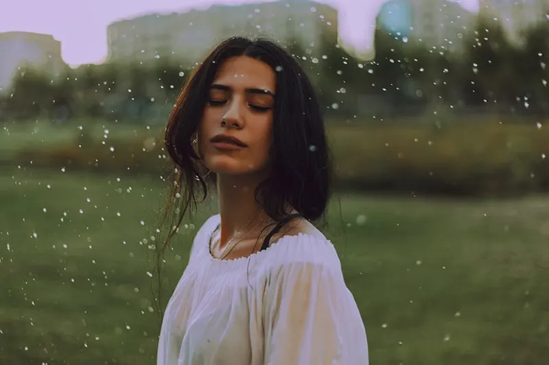 eine kindische Frau, die mit geschlossenen Augen auf dem Regen steht