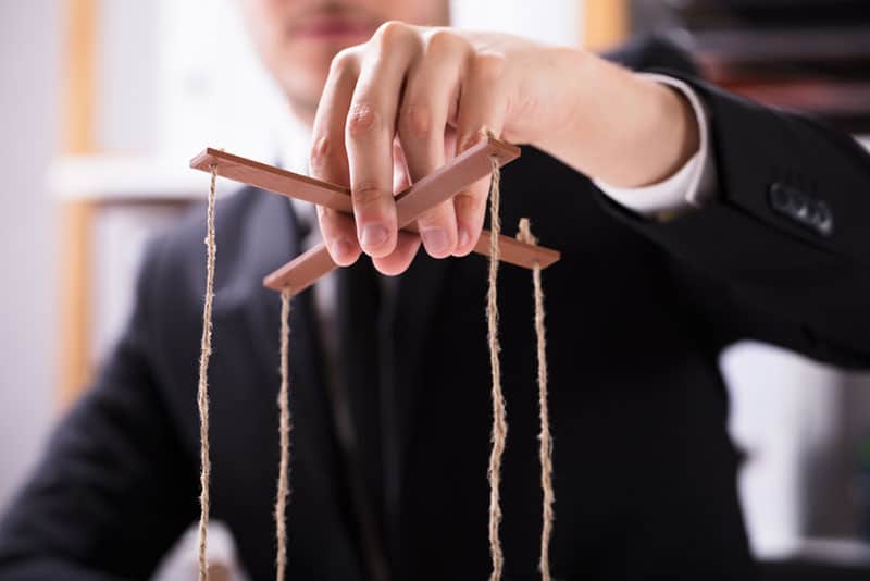 Mann hält manipulierende Marionettenschnur