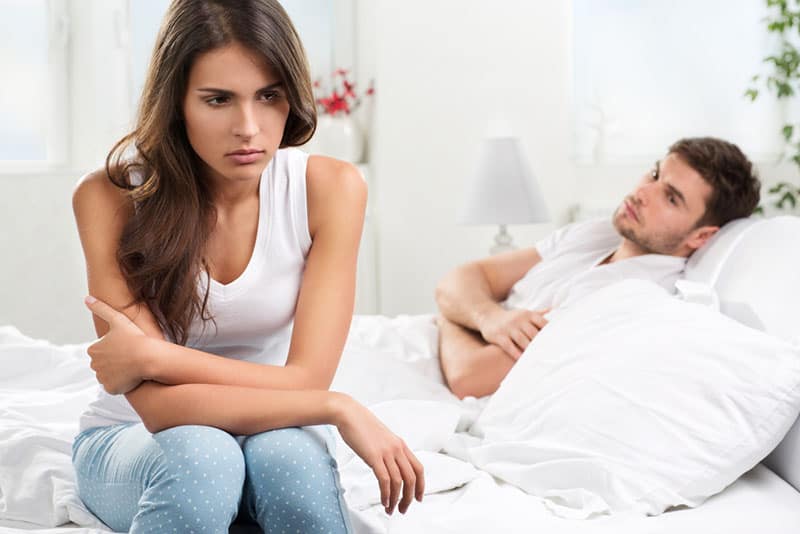 Mann im Bett liegend, während Frau distanziert
