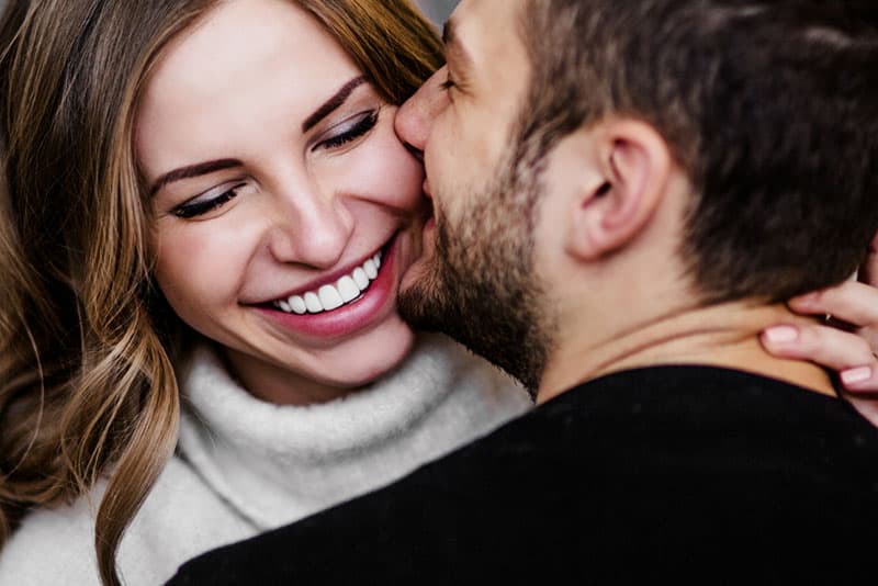 Mann küsst lächelnde Frau