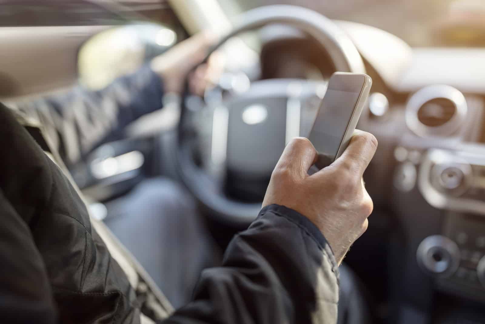 Mann schreibt beim Autofahren eine SMS