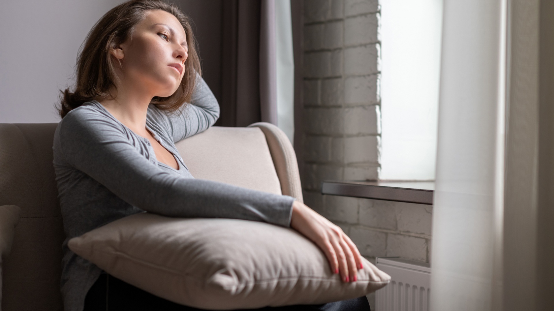 traurige frau sitzt am fenster und denkt nach