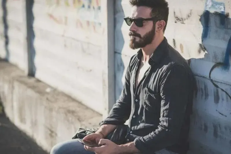 Mann mit Sonnenbrille sitzt im Freien