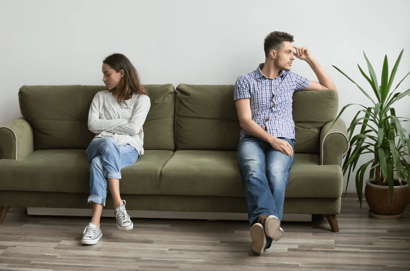 Wütendes Paar, das nach verletzenden Worten mit Abstand auf der Couch sitzt