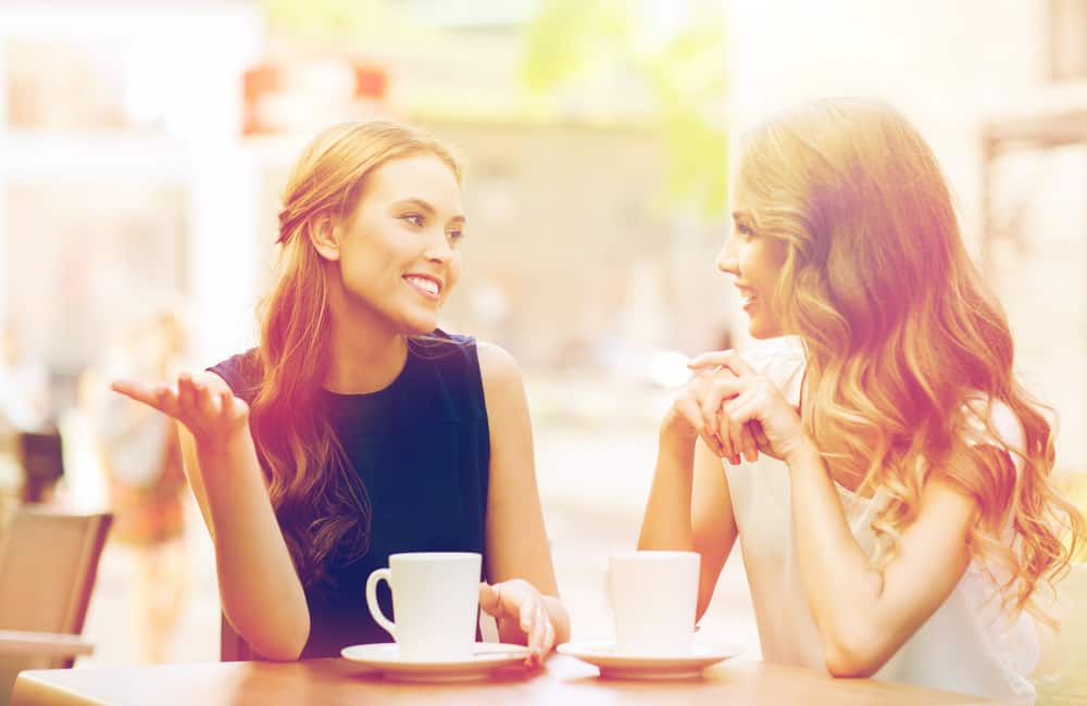 Zwei lächelnde Freunde sitzen und reden beim Kaffee