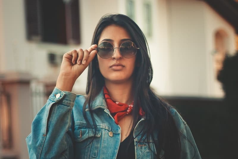 attraktive Brünette mit Sonnenbrille und rotem Schal um den Hals