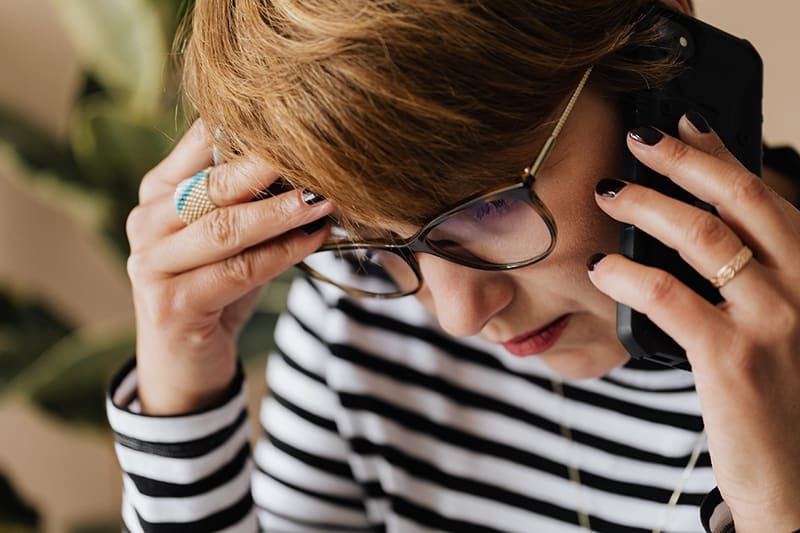 besorgte Frau, die ein Telefongespräch führt und ihren Kopf berührt