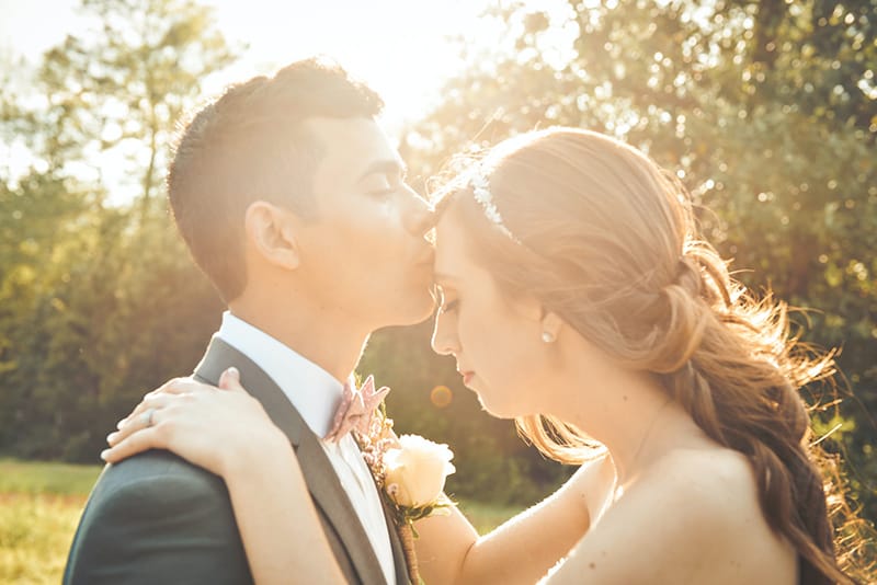Ein Bräutigam küsst seine Braut auf die Stirn