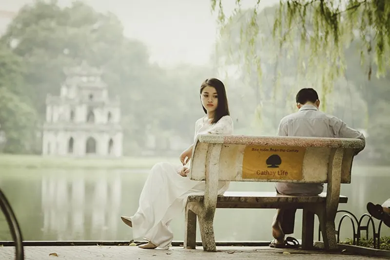Ein Mann ignoriert eine traurige Frau, während beide auf der Bank sitzen