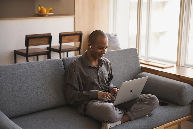 Ein Mann benutzt einen Laptop und plaudert, während er auf der Couch sitzt