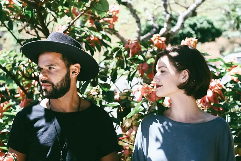 Ein Mann und eine Frau schauen beiseite, während sie in der Nähe der Pflanzen stehen
