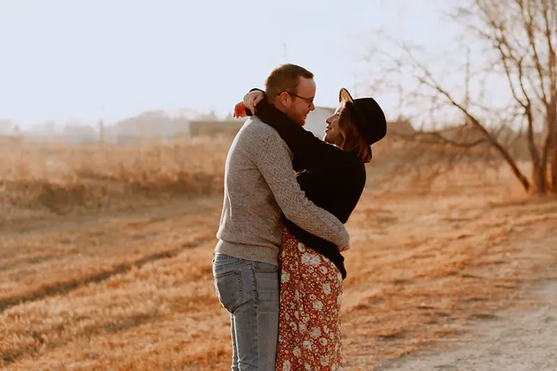 Ein Mann und eine Frau umarmen sich, während sie in der Nähe des Feldes stehen