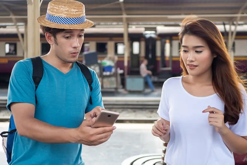 Ein Mann zeigt ein Smartphone einer Frau, während er sich seltsam verhält