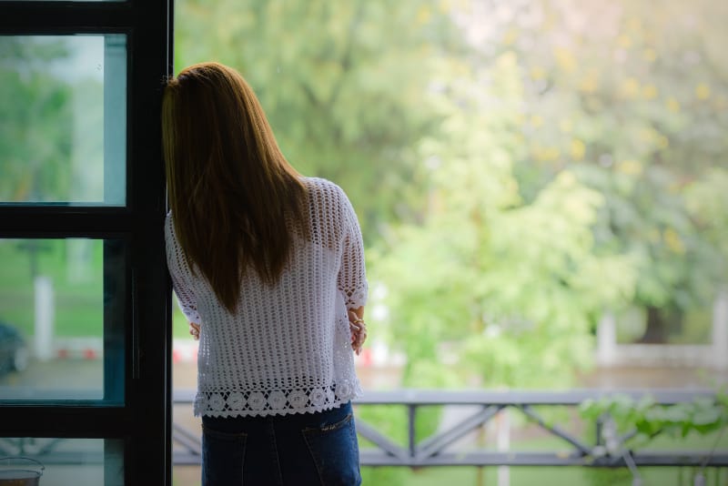 ein Mädchen, das sich gegen einen Schaft am Fenster lehnt