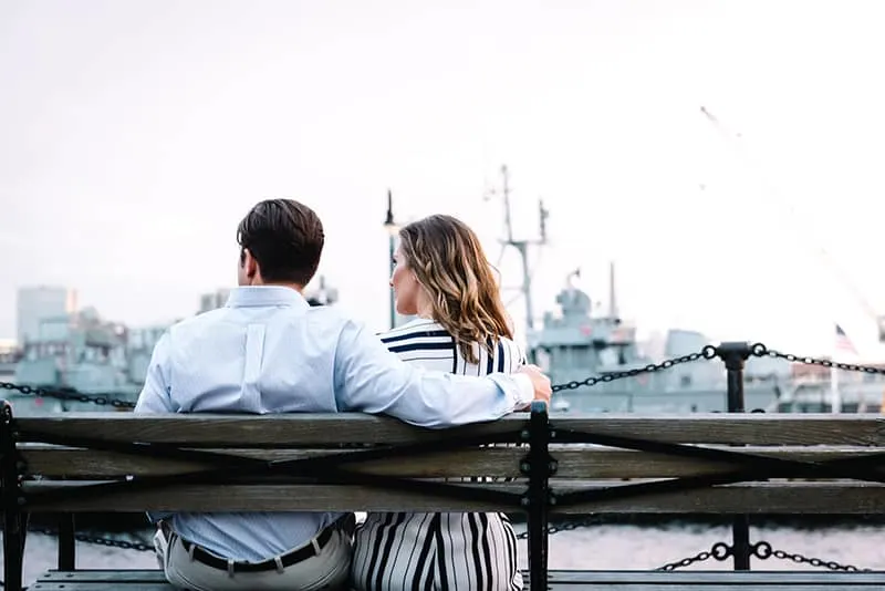 Ein Paar sitzt auf der Bank in der Nähe des Gewässers und redet