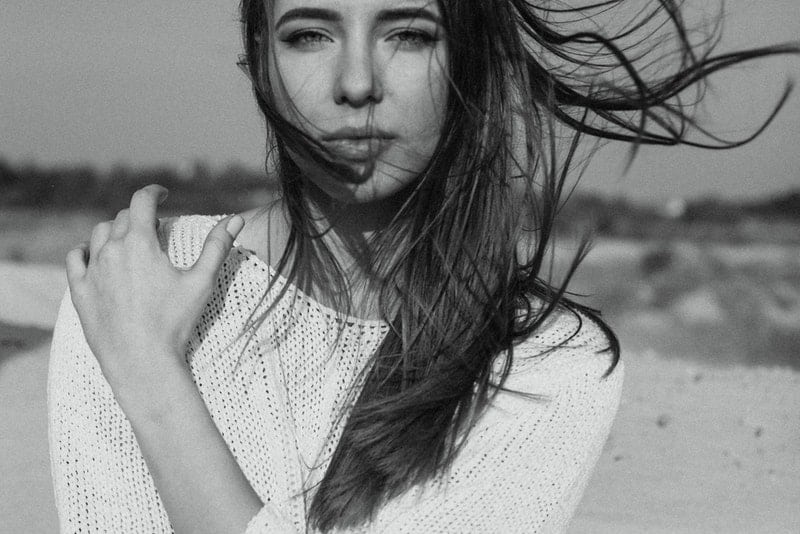 ein Schwarzweißfoto einer Frau, deren Wind ihre langen Haare trägt