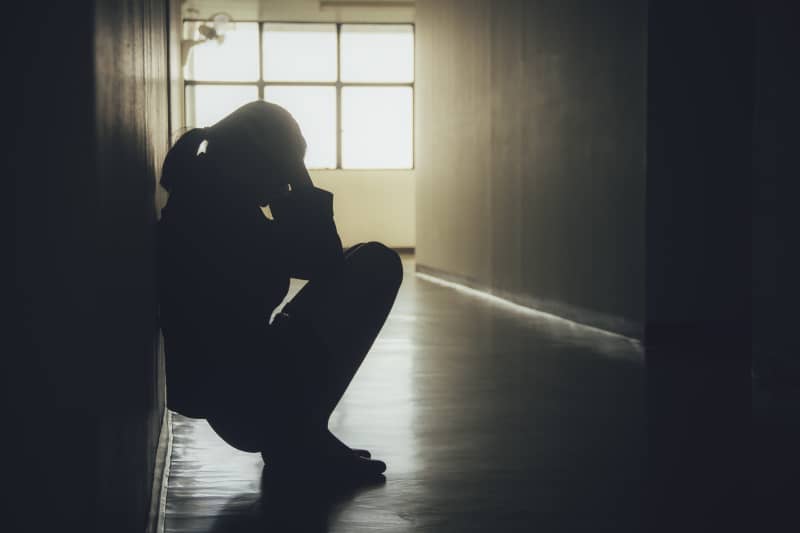 ein depressives Mädchen sitzt auf dem Flur