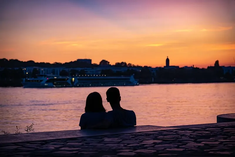 ein liebevolles Paar, das am Strand sitzt und einen Sonnenuntergang beobachtet