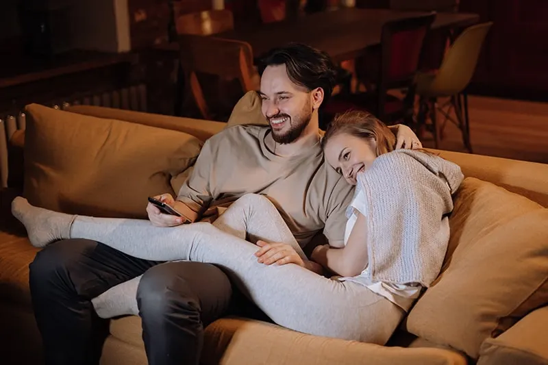 ein liebendes Paar sitzt auf der Couch und lacht zusammen