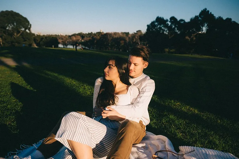 Ein liebevolles Paar umarmt sich, während es auf der Decke im Park sitzt