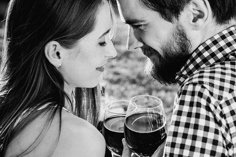 ein liebevolles Paar, das sich ansieht, während es ein Glas Wein hält
