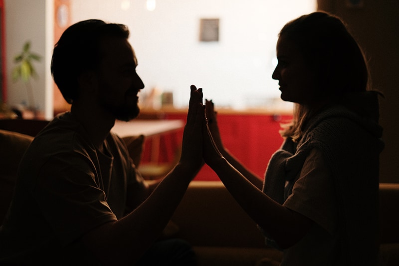 Ein liebevolles Paar, das sich abends auf dem Sofa auf die Handflächen setzt