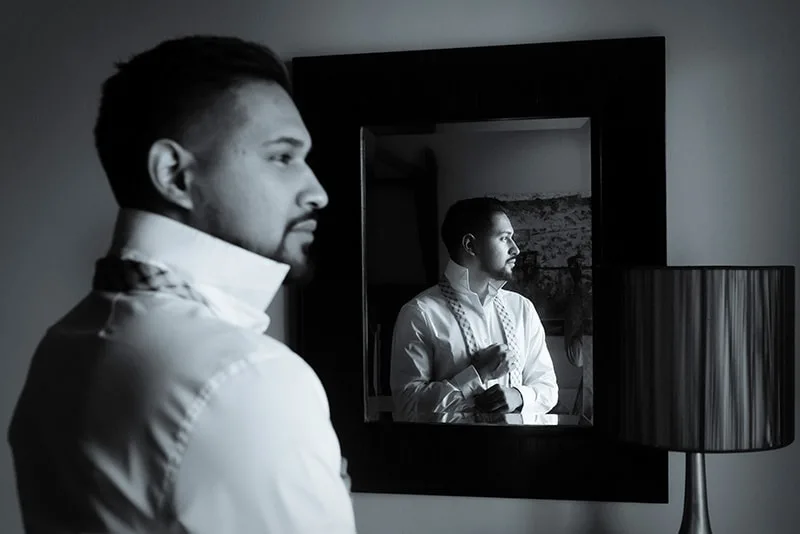 Ein selbstbewusster Mann, der in der Nähe des Spiegels steht und sein Hemd faltet