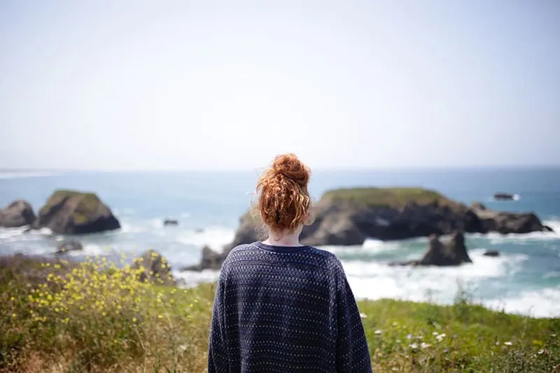 eine Frau, die allein steht und das Meer beobachtet