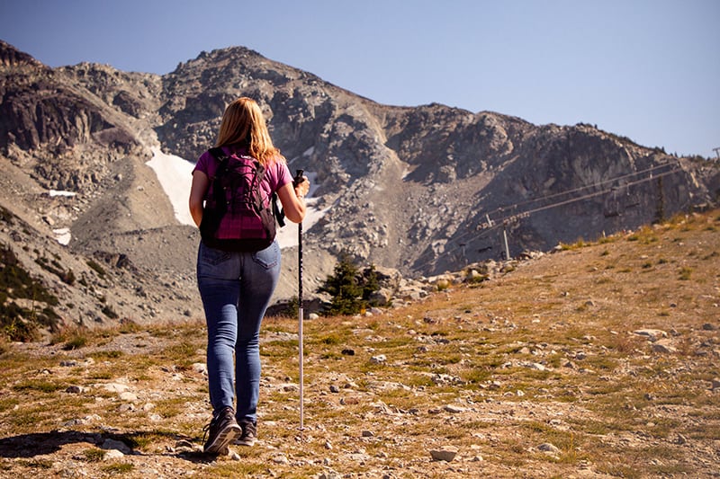 eine Frau, die auf einer Wiese mit Blick auf die Berge geht