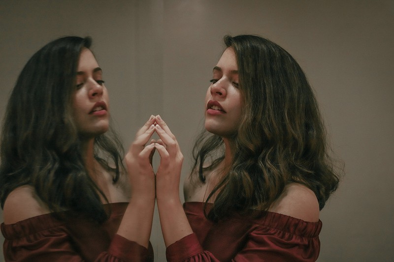 eine Frau, die den Spiegel berührt, während sie sich selbst ansieht