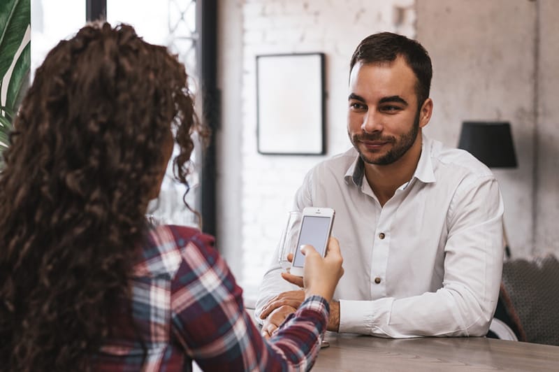 eine Frau, die ein Smartphone benutzt, während sie sich mit einem Mann verabredet