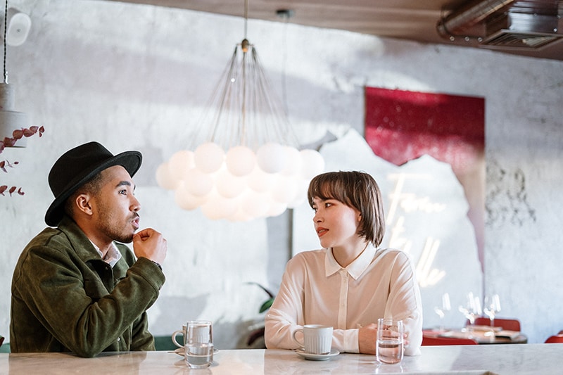 eine Frau, die einem Mann zuhört, während er in einem Café sitzt