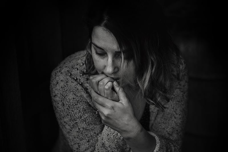 eine Frau, die sich schuldig fühlt und ihre Lippen mit der Hand berührt