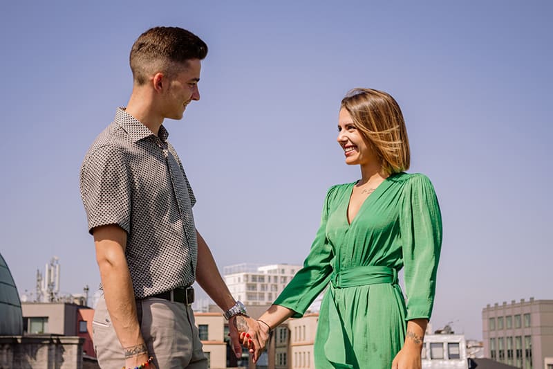 eine Frau im eleganten Kleid Händchen haltend mit einem Mann beim Stehen im Freien
