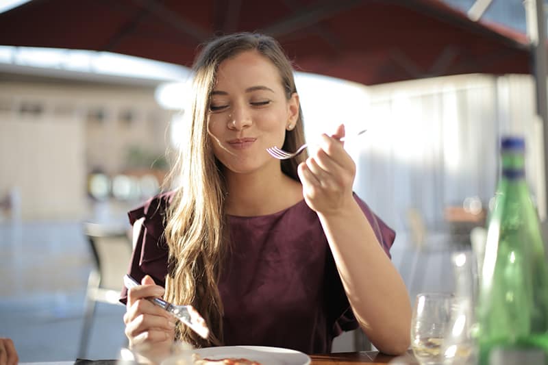 uma mulher com uma blusa roxa comendo no restaurante