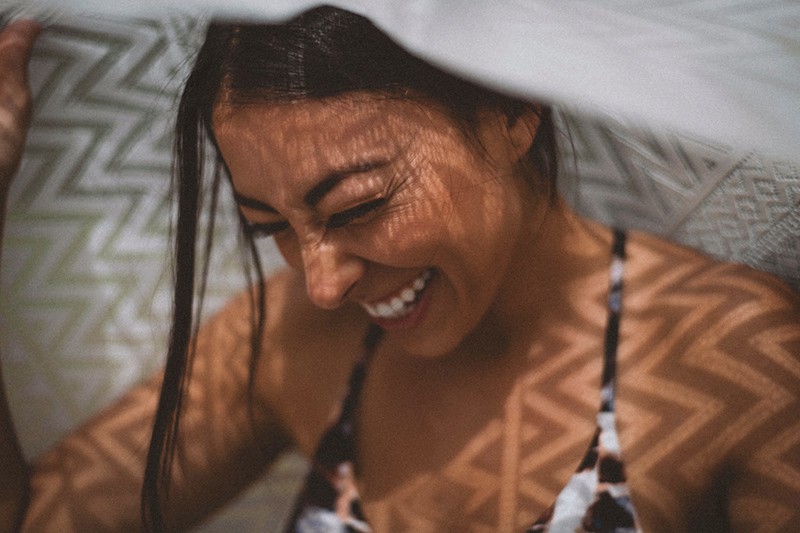 eine Frau mit weißem Textil bedeckt beim Lachen