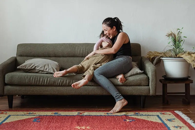 eine glückliche Frau, die ihr Kind umarmt, während sie auf der Couch sitzt