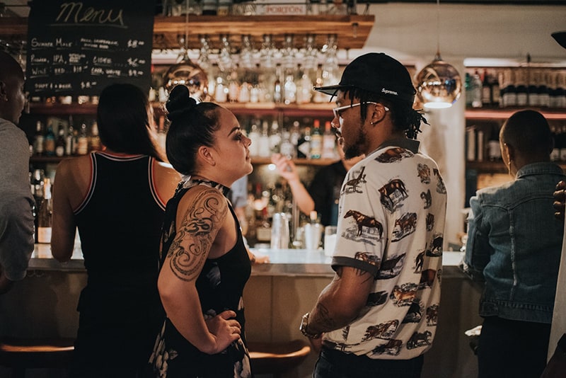 Eine Frau und ein Mann stehen sich gegenüber, während sie in der Bar stehen