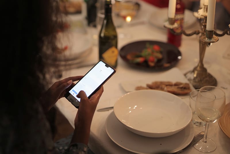 eine Person, die Smartphone während eines Abendessens hält