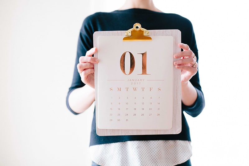 eine Person, die im Stehen einen Kalender hält