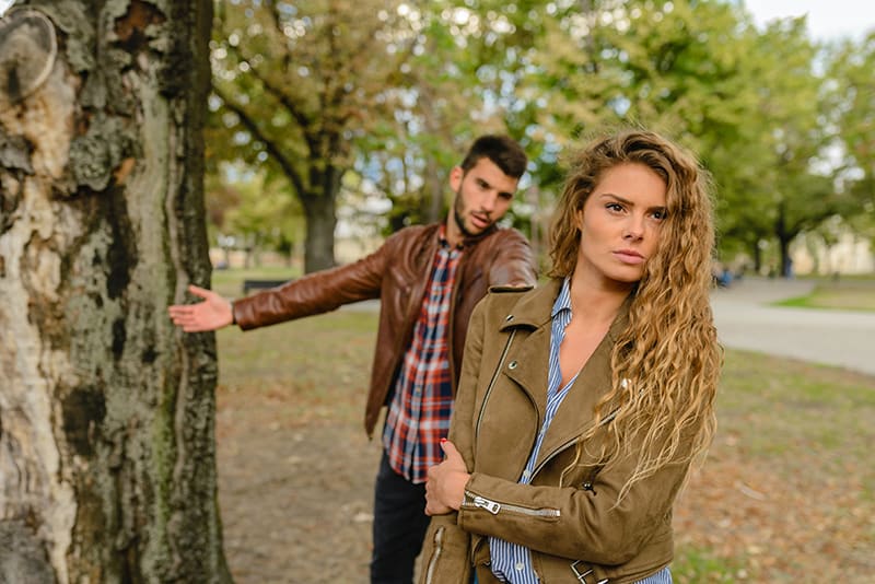 eine beleidigte Frau, die sich im Park dem klagenden Mann zuwendet