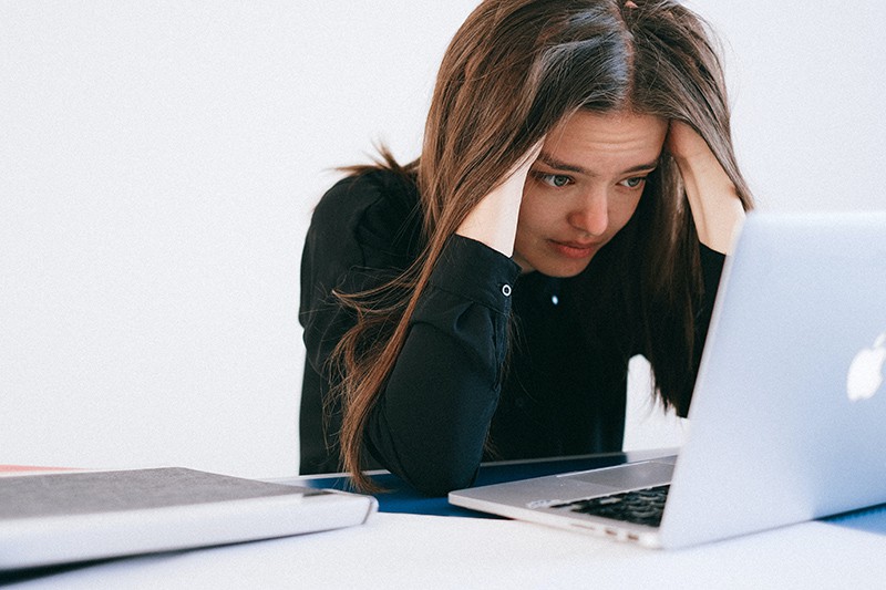 eine gestresste Frau, die einen Laptop betrachtet, während sie im Büro sitzt