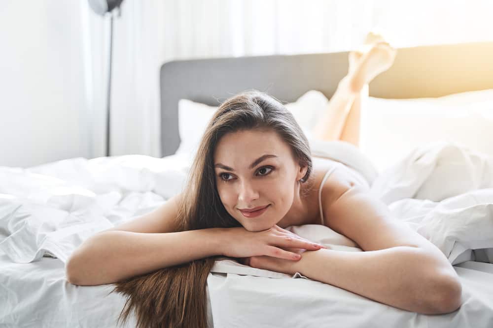 eine schöne junge Frau, die lächelnd auf dem Bett liegt