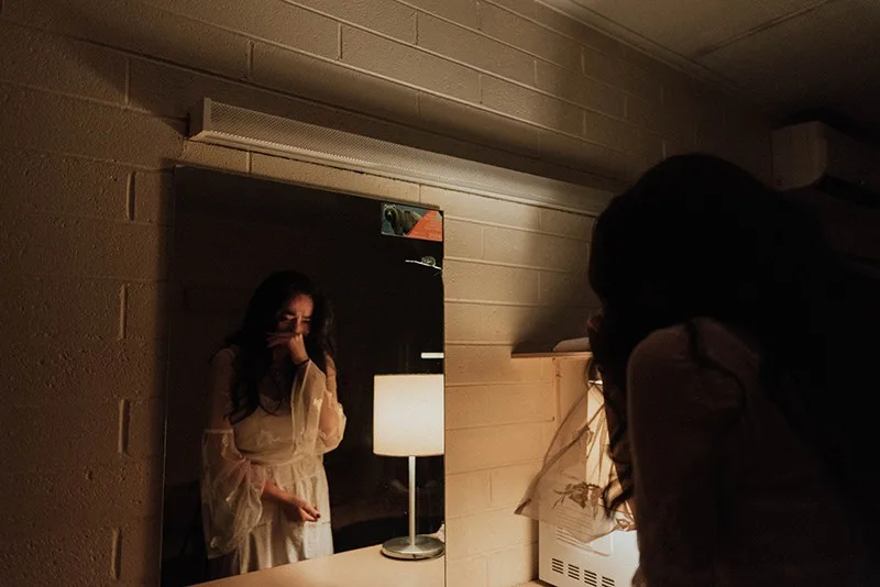 eine weinende Frau vor dem Spiegel, während sie im Raum steht