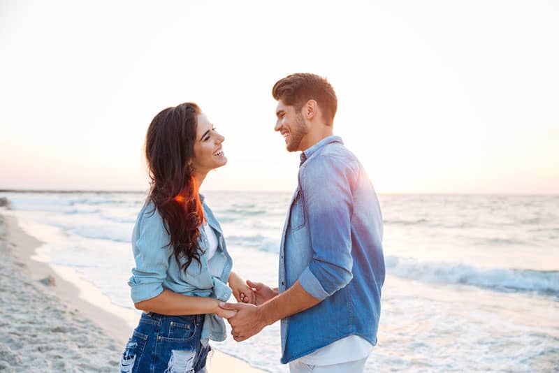 glückliches Paar, das Hände am Strand hält