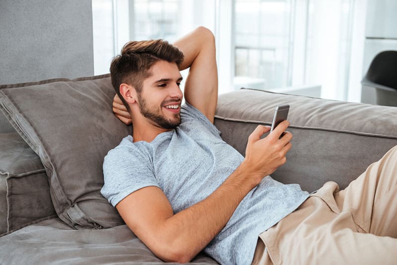 glücklicher Mann, der Telefon ansieht