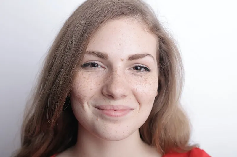 junge Frau mit Sommersprossen im Gesicht ohne Make-up